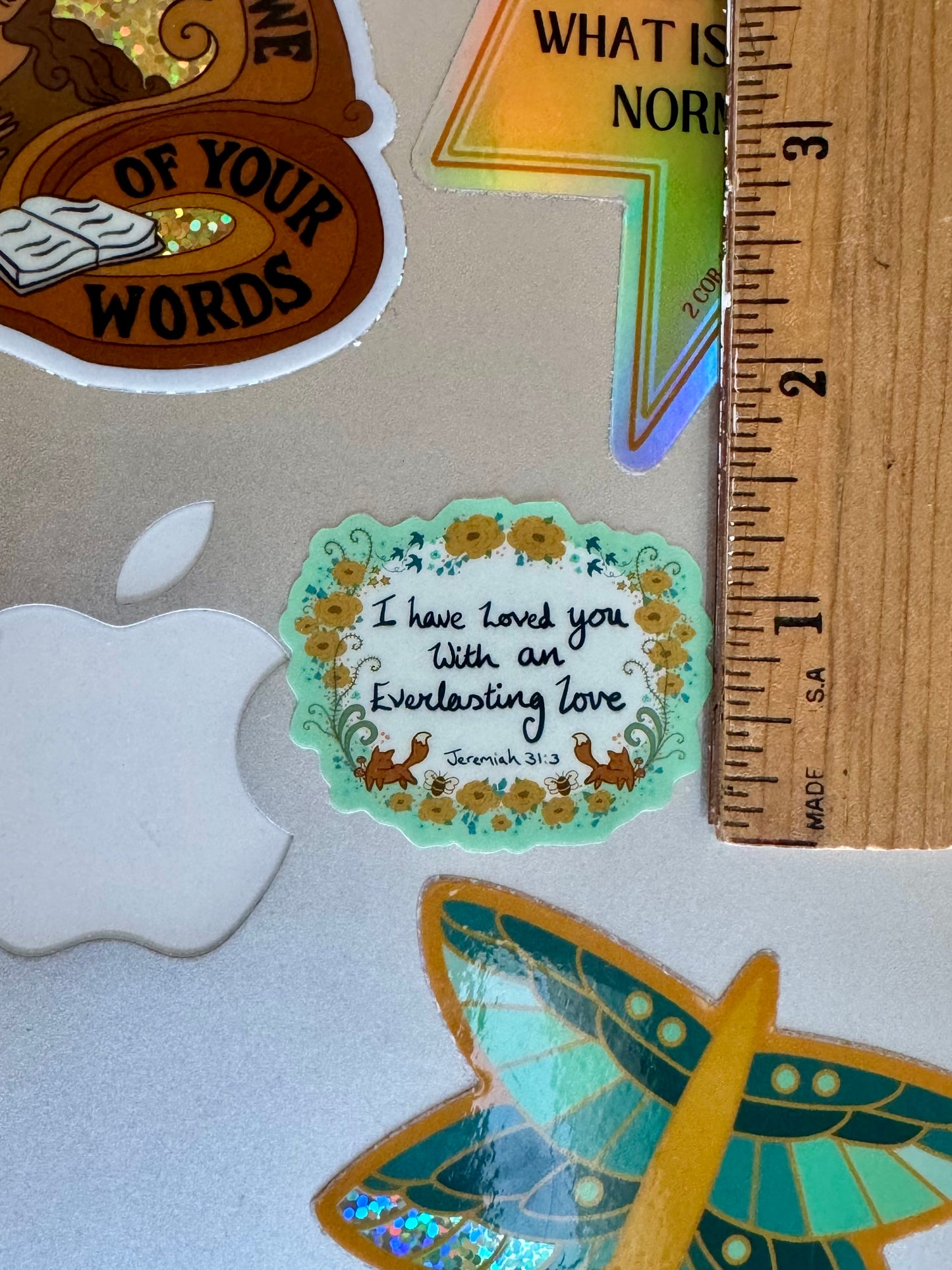 bible sticker with the scripture I have loved you with an everlasting love written onthe sticker, placed next to a ruler for scale, showing it is around 1 1/4" high