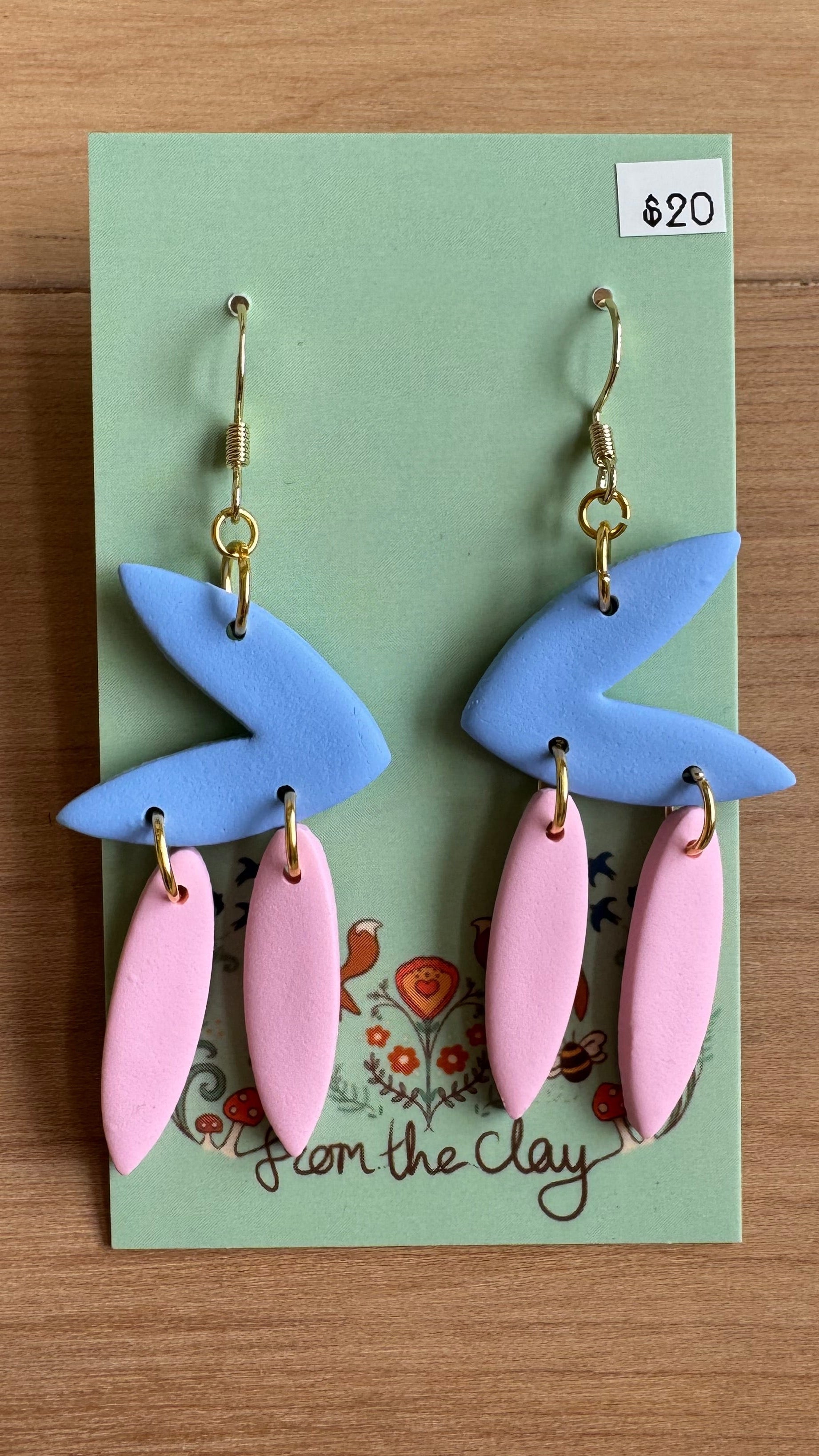 Pair of pastel blue and pink earrings on a green card