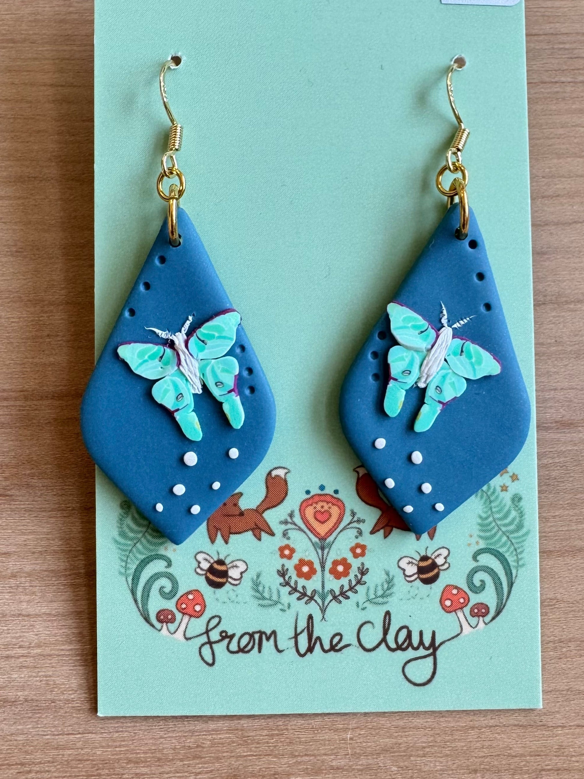 Blue teardrop earrings with flying Luna Moth made entirely of polymer clay.